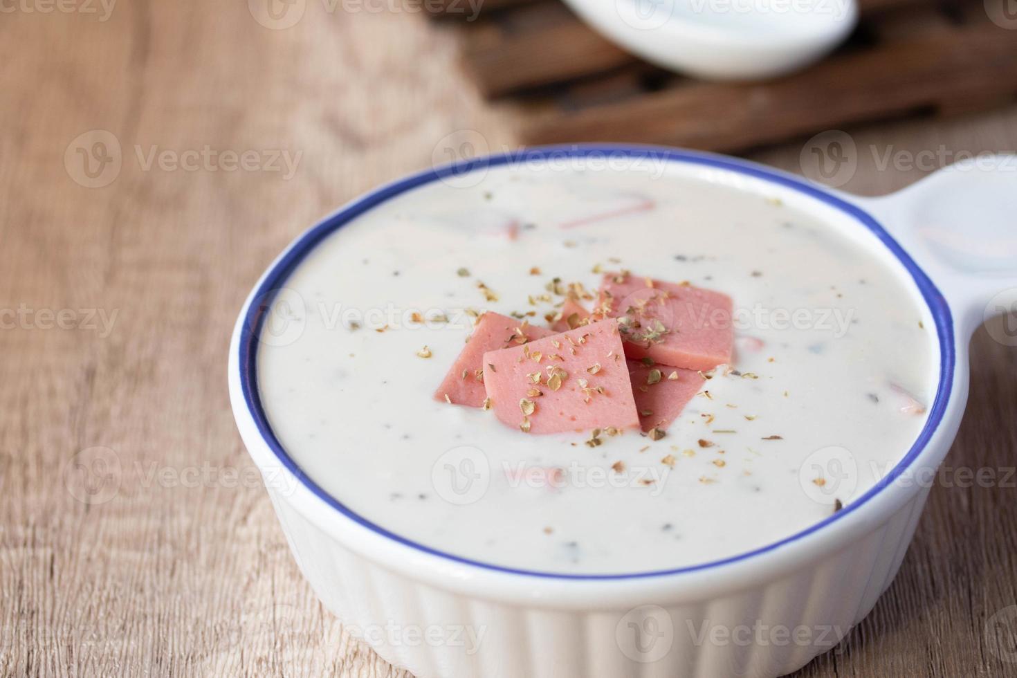 Cheese soup with vegetables and ham with toast on the table close-up horizontal sprinkle oregano in white bowl photo