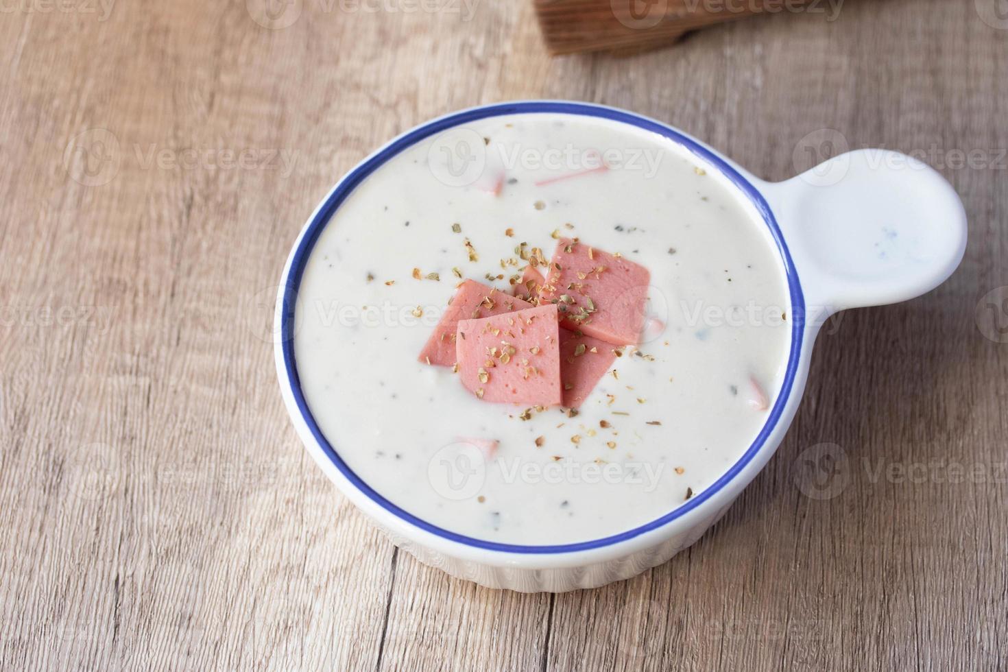 Cheese soup with vegetables and ham with toast on the table close-up horizontal sprinkle oregano in white bowl photo