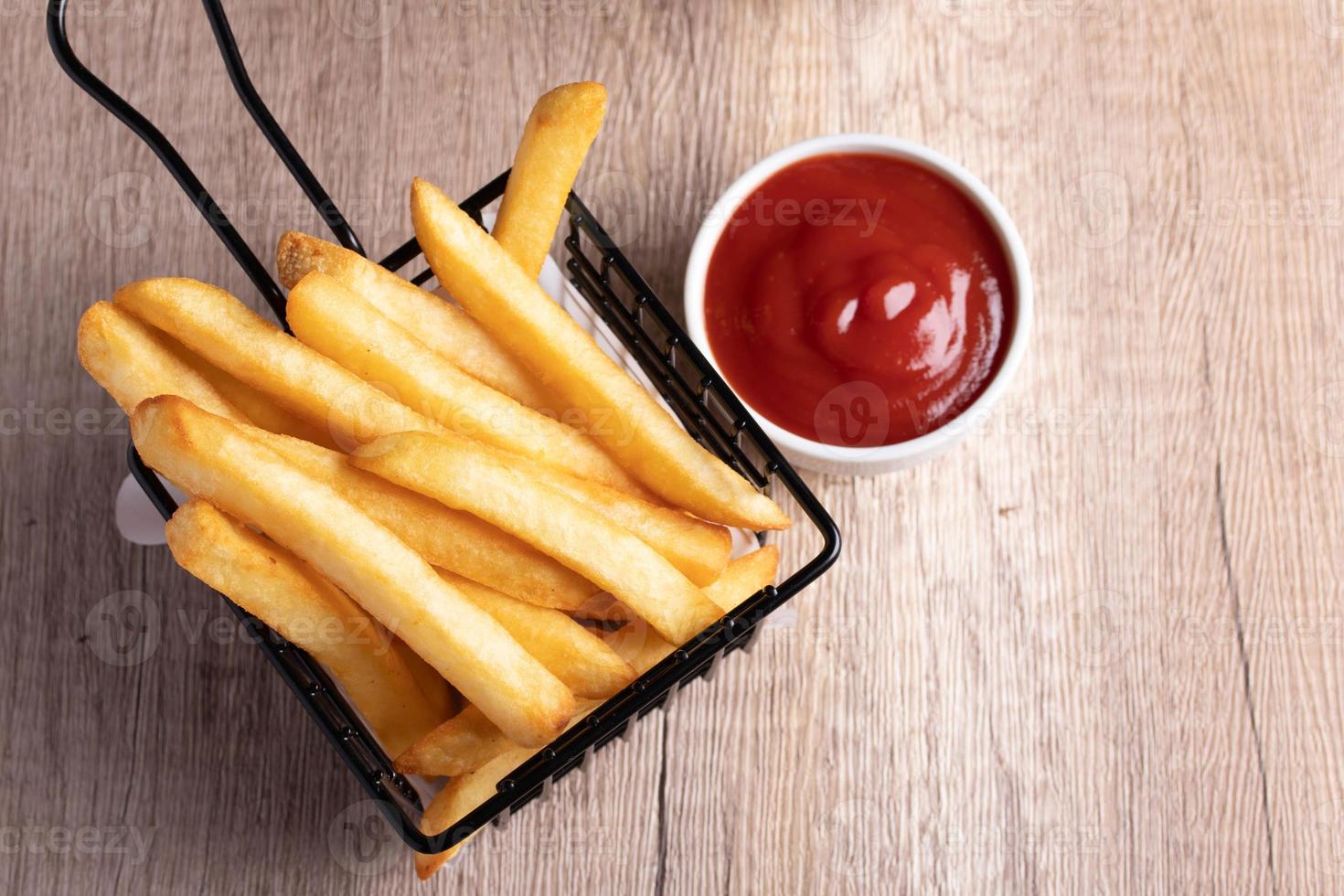 French fries in a black basket with tomato sauce photo
