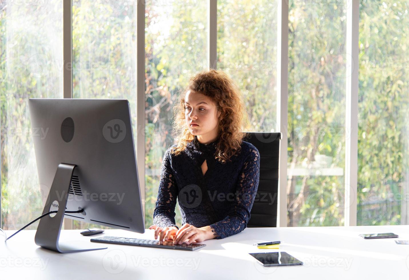 atractiva y hermosa mujer de negocios que trabaja con una computadora en la oficina o el hogar modernos foto