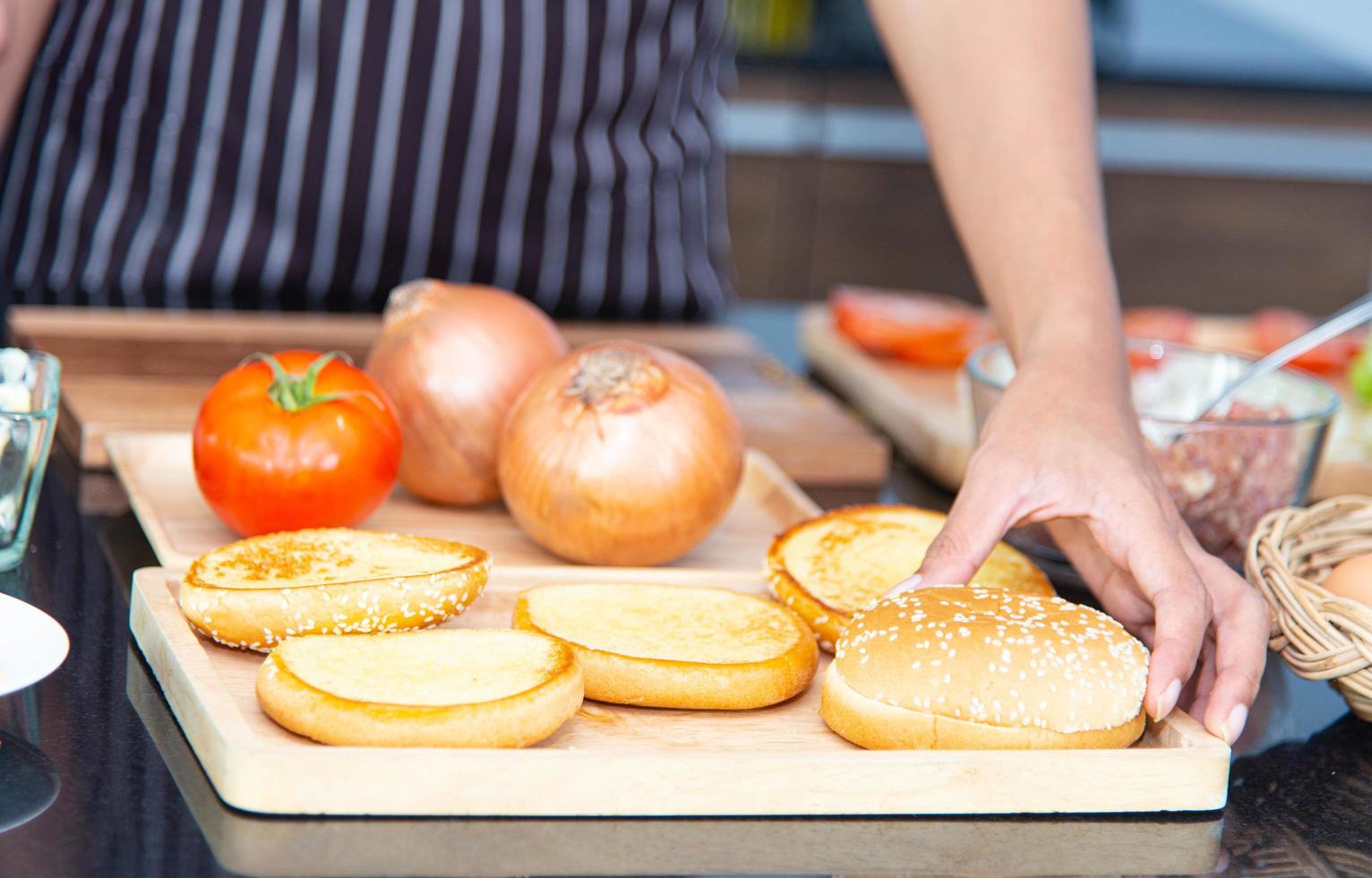 Chef preparing bread onion tomato and making hamburger in the kitchen. photo