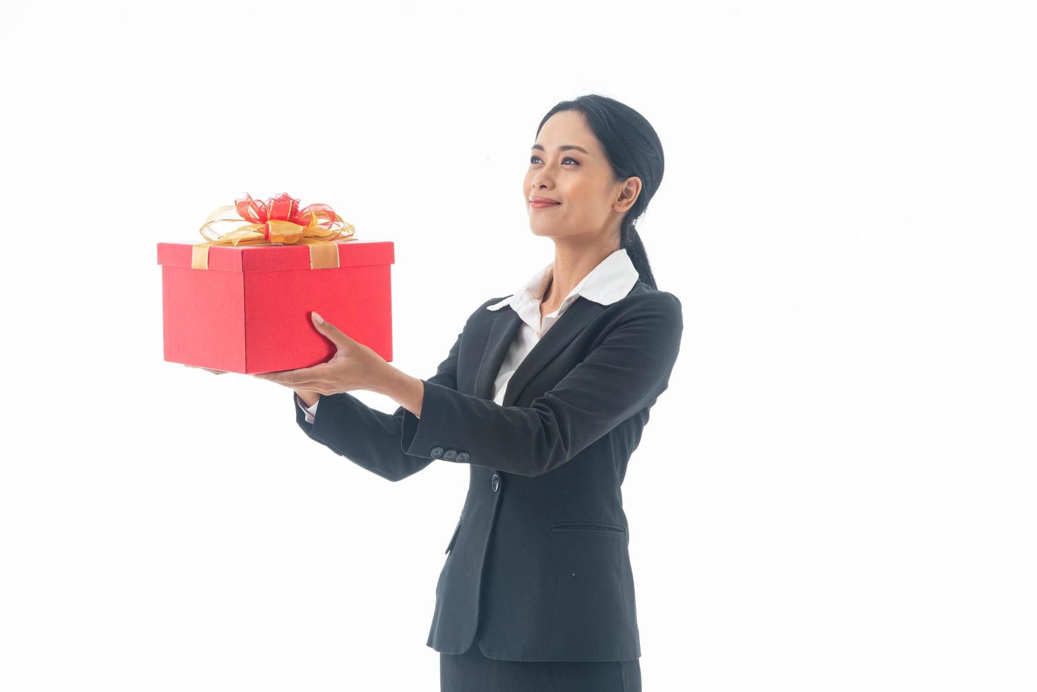 Portrait young beautiful smiling happy woman wear black suit  holding red gift box looking at camera on isolated white background. photo