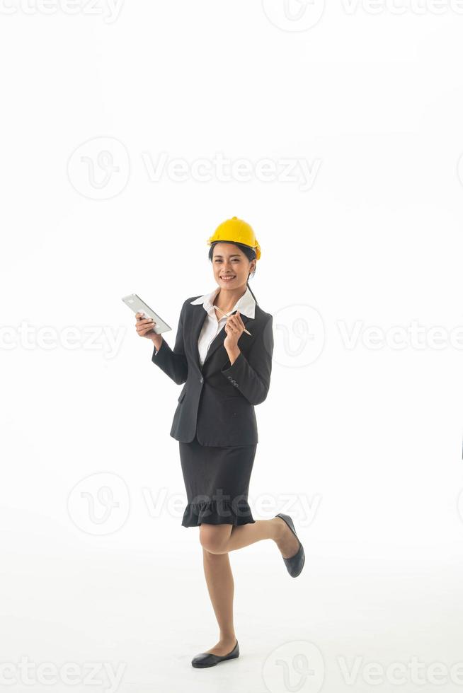 Young engineer woman wear black suit and yellow safety helmet holding note or tablet on isolated white background. photo