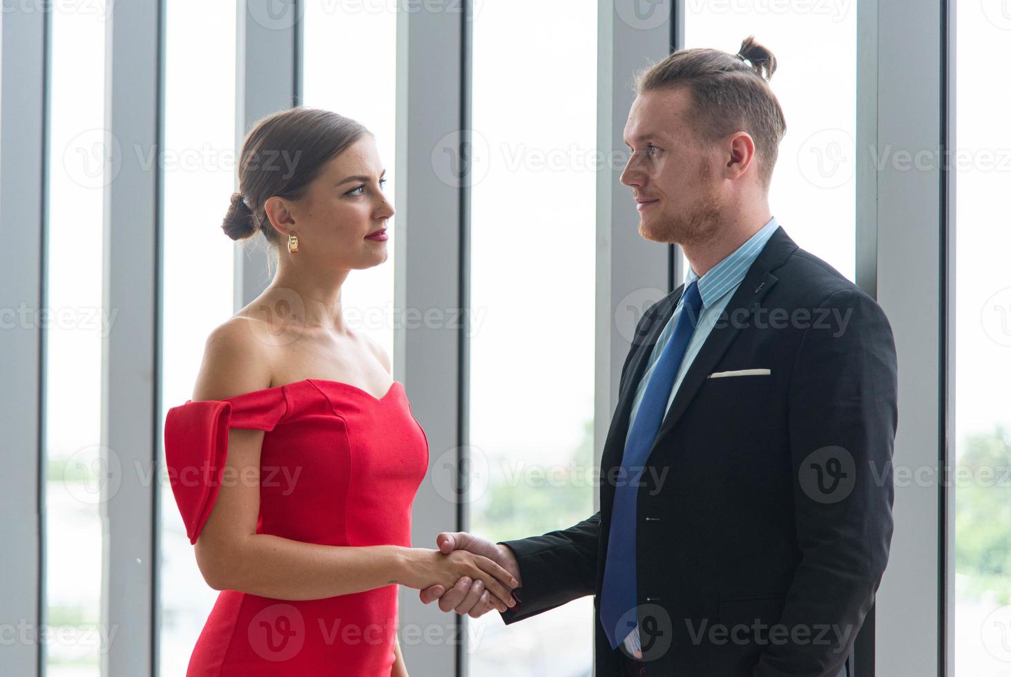 Business partners success deal concept. Smart businessman and businesswoman shaking hands after success deal meeting at modern office. photo