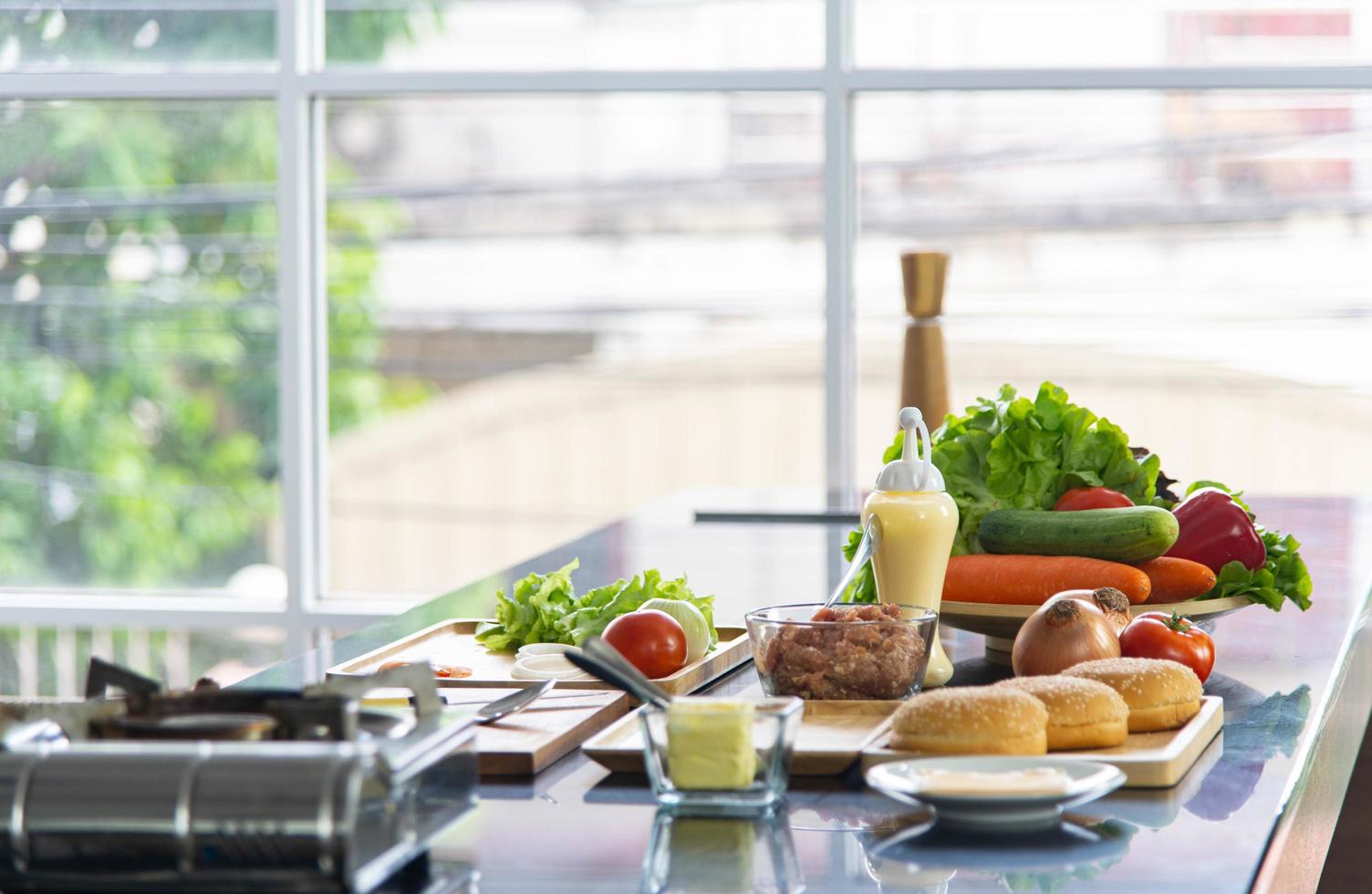 alimentos saludables, vegetales crudos orgánicos y utensilios para cocinar en la mesa de la cocina moderna foto