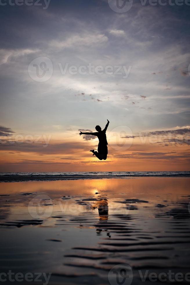 Silhouette of man Jumping on Beach at Sunset photo