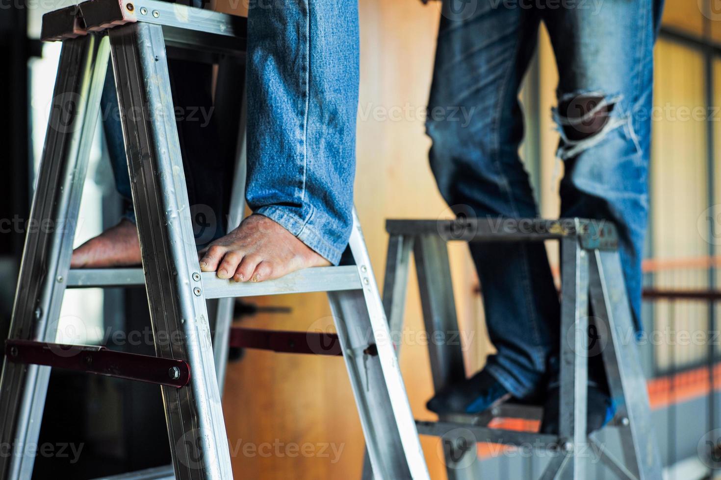 enfoque selectivo en la escalera de aluminio con pies desenfocados de los trabajadores que trabajan en ella foto