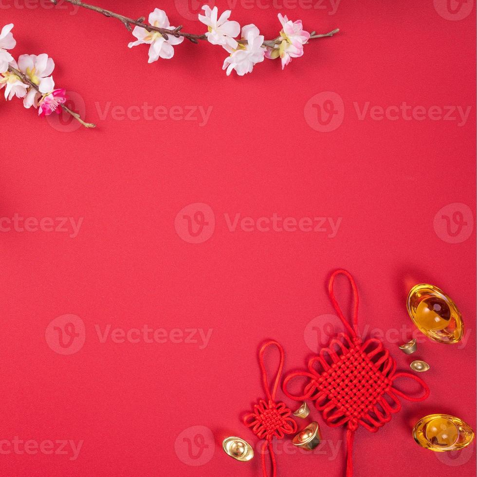 Design concept of Chinese lunar new year - Beautiful Chinese knot with plum blossom isolated on red background, flat lay, top view, overhead layout. photo