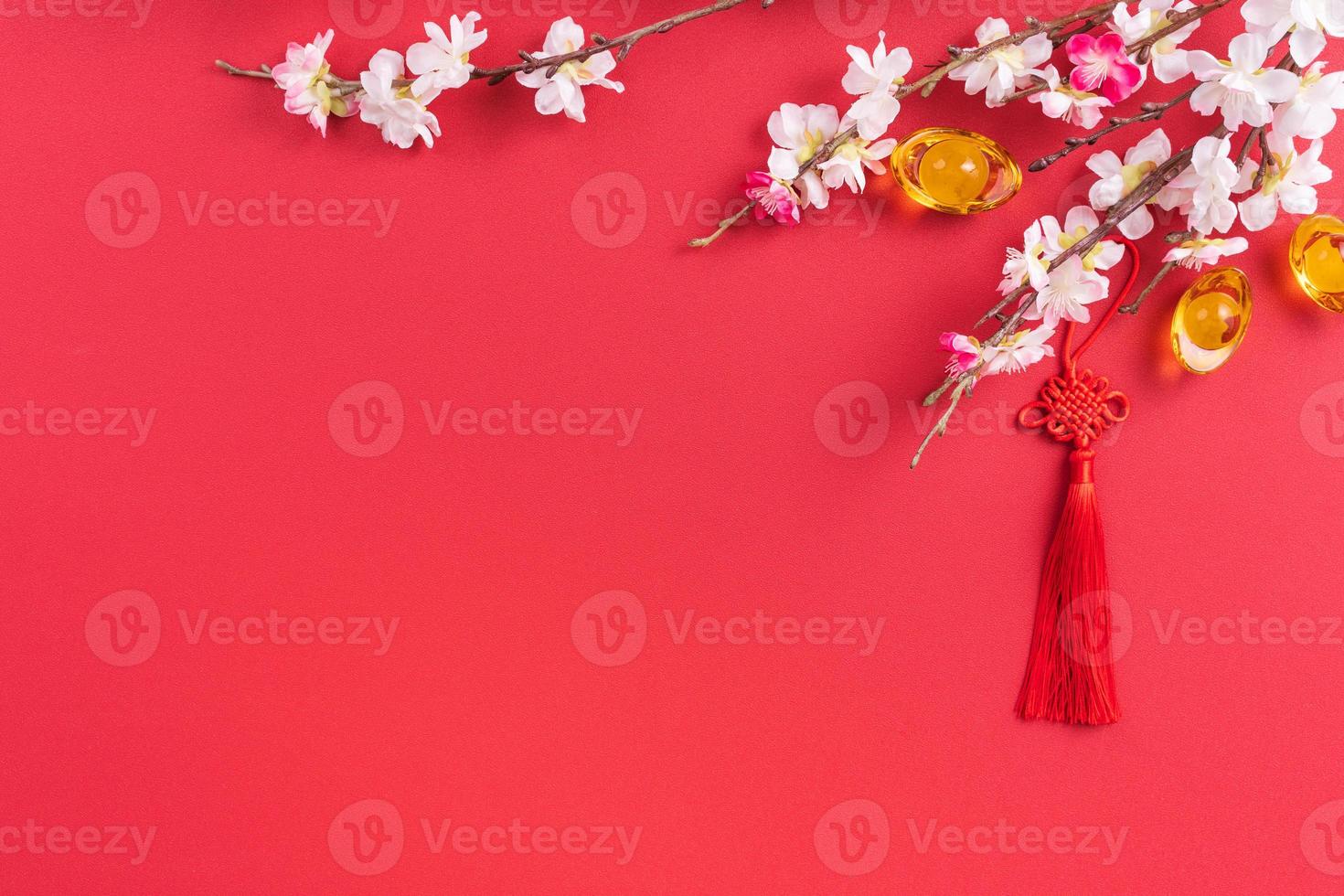 Design concept of Chinese lunar new year - Beautiful Chinese knot with plum blossom isolated on red background, flat lay, top view, overhead layout. photo