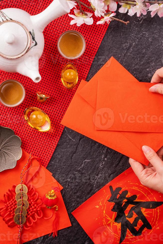 concepto de diseño del año nuevo lunar chino de enero - mujer sosteniendo, dando sobres rojos ang pow, hong bao por dinero de la suerte, vista superior, endecha plana, arriba. la palabra 'chun' significa próxima primavera. foto