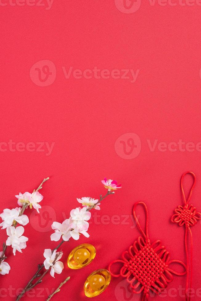 Design concept of Chinese lunar new year - Beautiful Chinese knot with plum blossom isolated on red background, flat lay, top view, overhead layout. photo