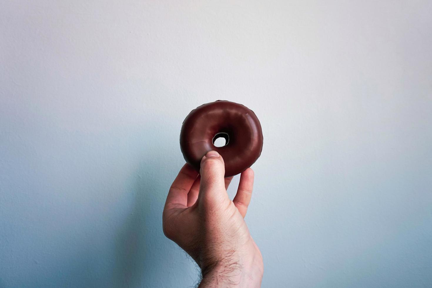 hand with a chocolate doughnut photo