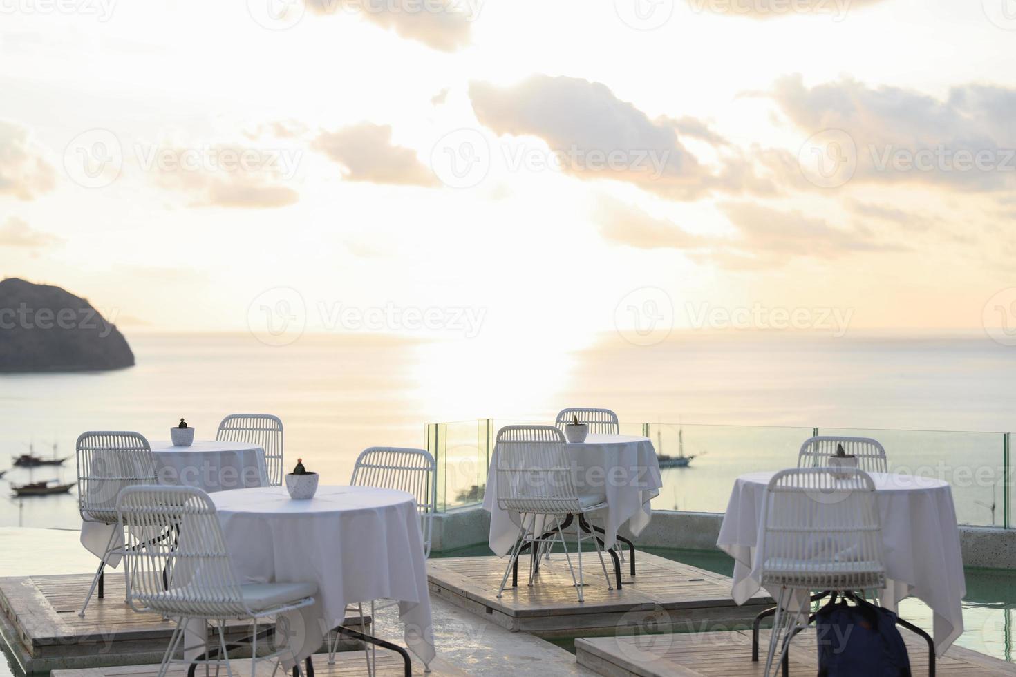 Cozy and romantic cafe with table and chairs on rooftop with sea and sunset view photo