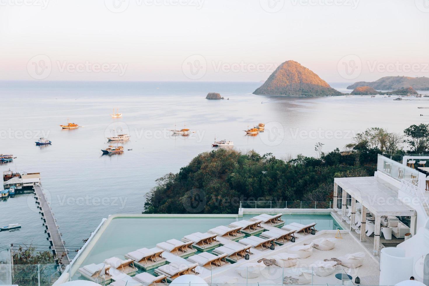 vista superior del mar con muchos barcos y una fila de sillas relajantes en el edificio de la azotea foto