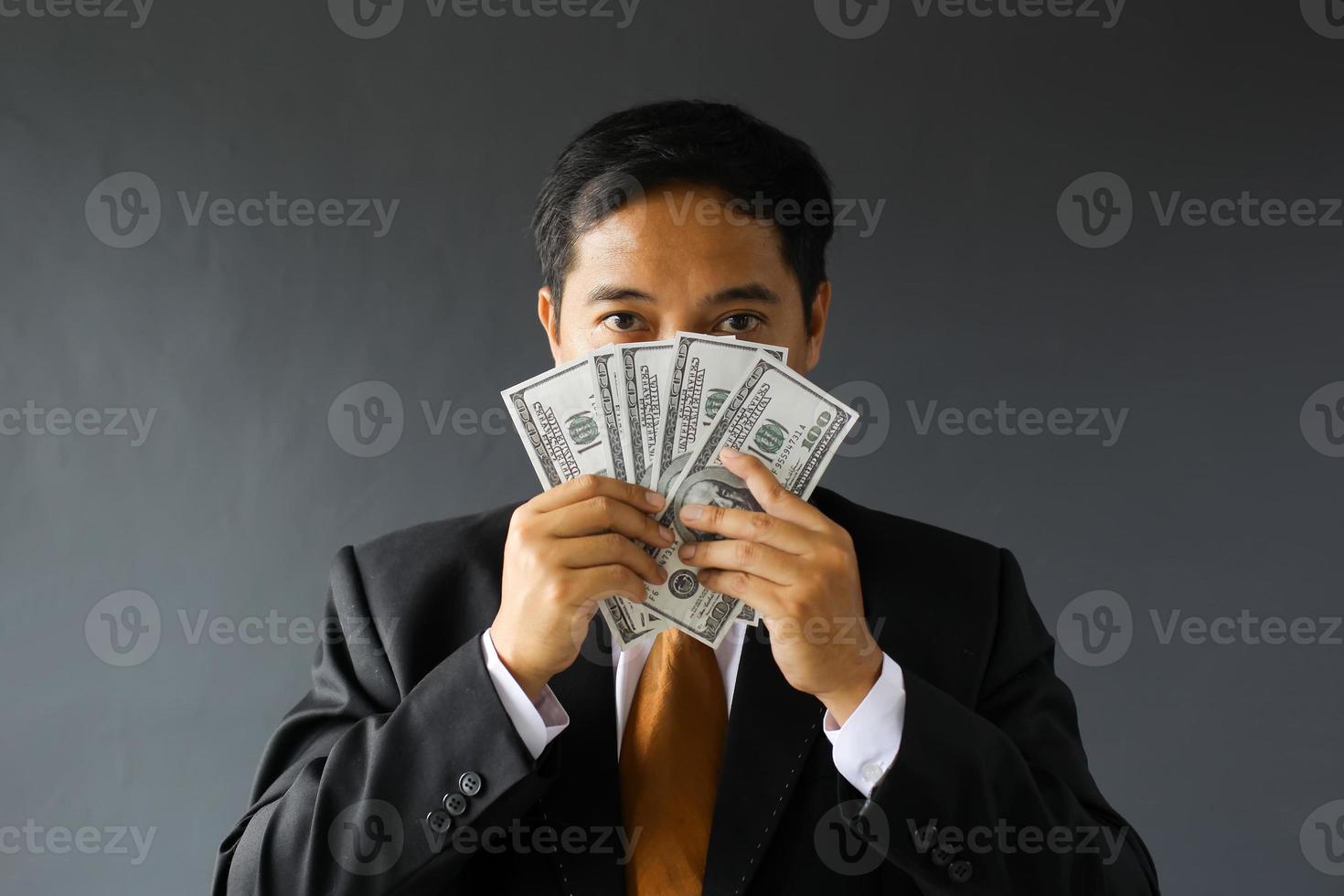 Greedy businessman in suit covering his face with dollar bills. Corruption and bribery concept photo