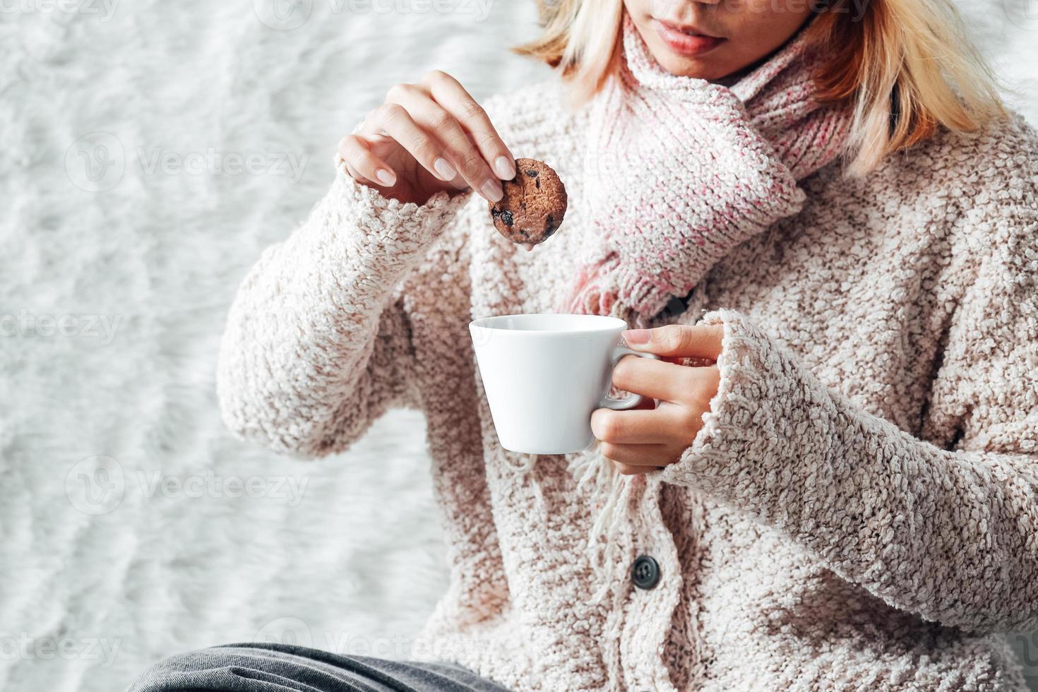 una chica disfrutando de unas galletas y una taza de chocolate caliente en la temporada de invierno foto