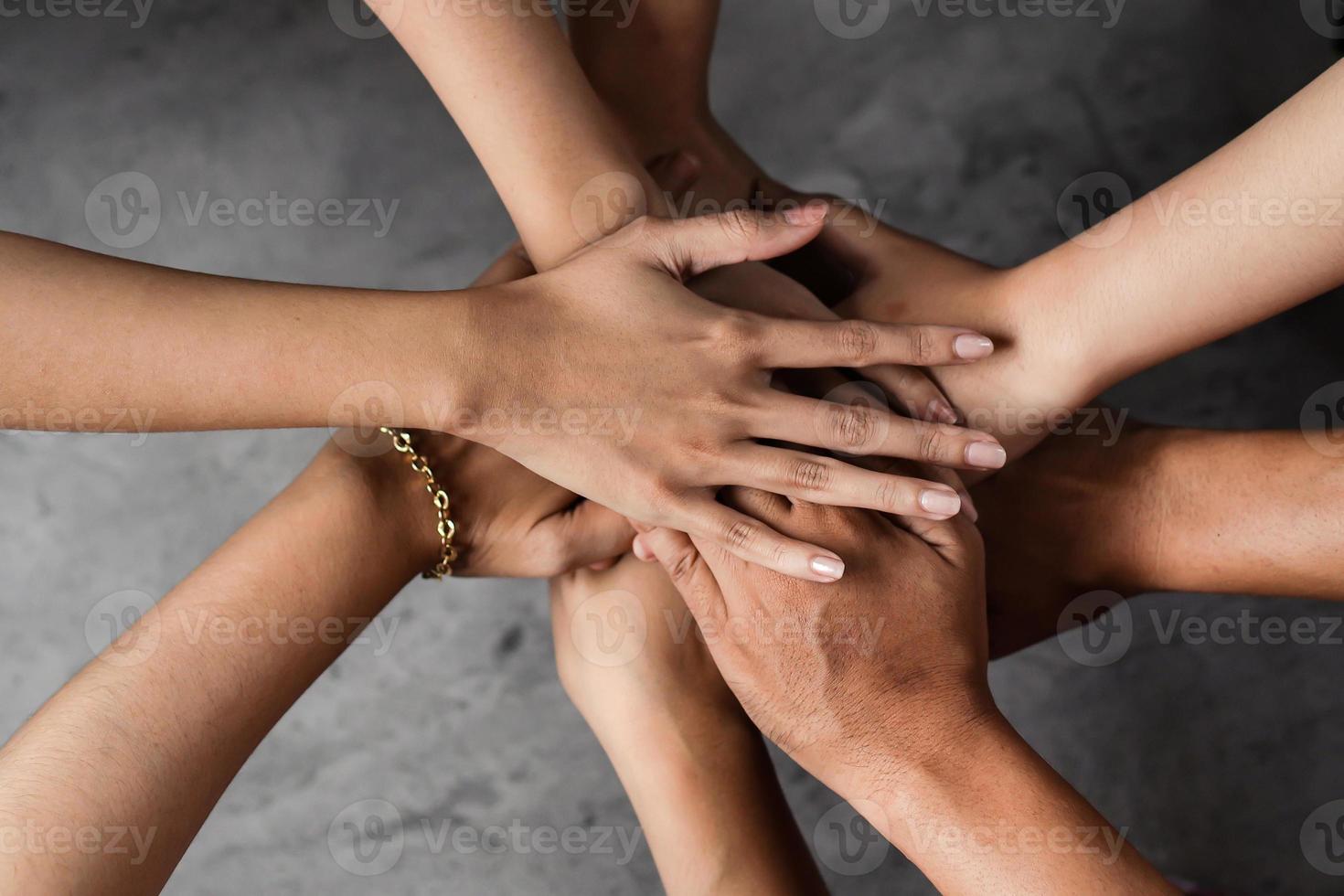 Close up top view of people putting their hands together. Stack of hands. Unity and teamwork concept. photo