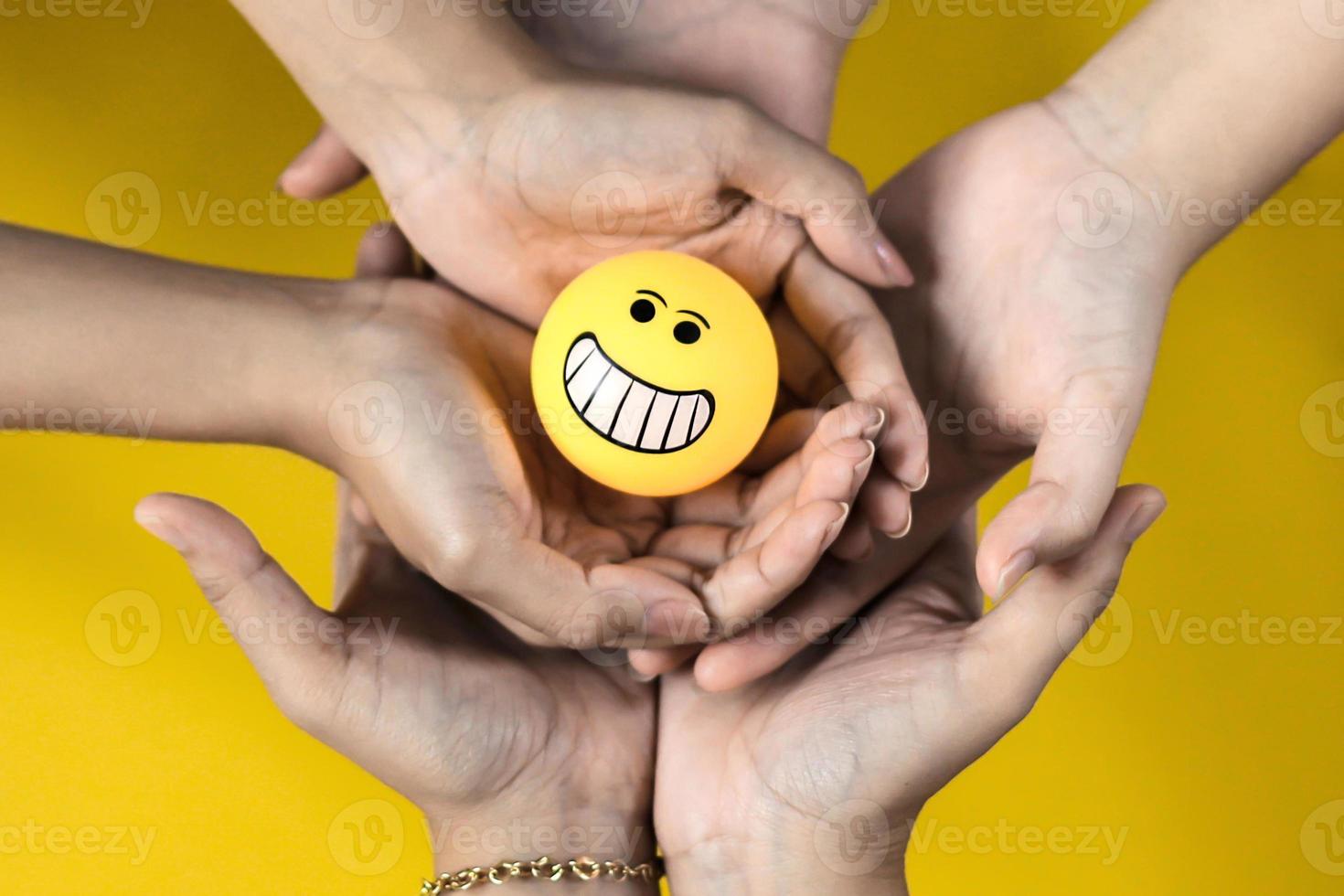 Stack of hands holding smiley emoticons together photo