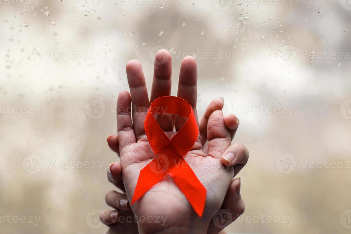 Red ribbon on hands for AIDS and cancer campaign background photo