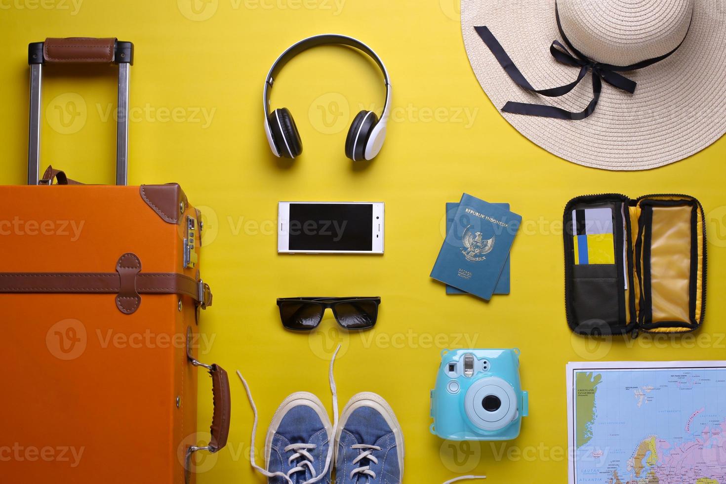 Flat lay orange suitcase with traveler accessories on yellow background. travel concept photo
