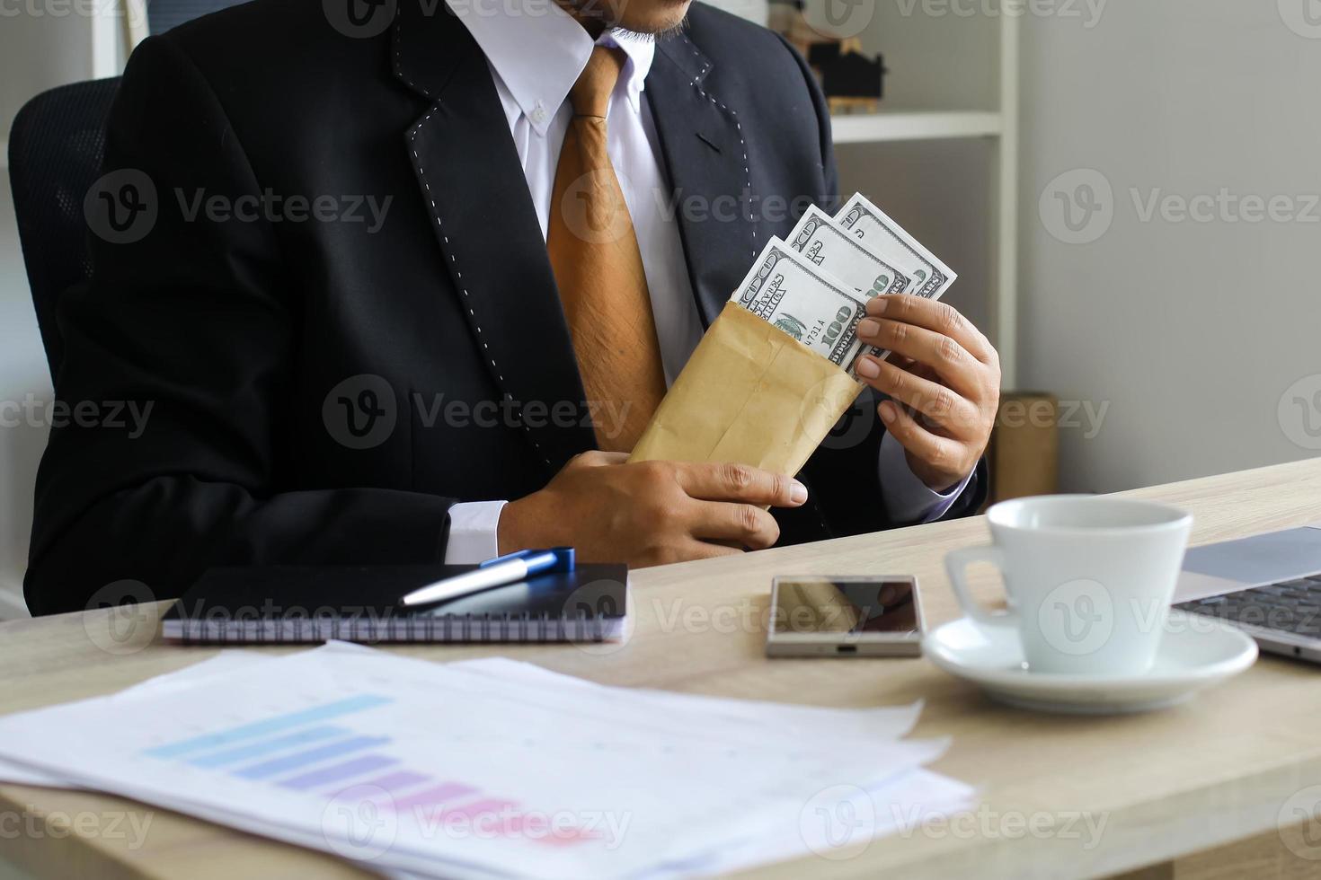corrupción y soborno, hombre de negocios que recibe dinero en su escritorio foto