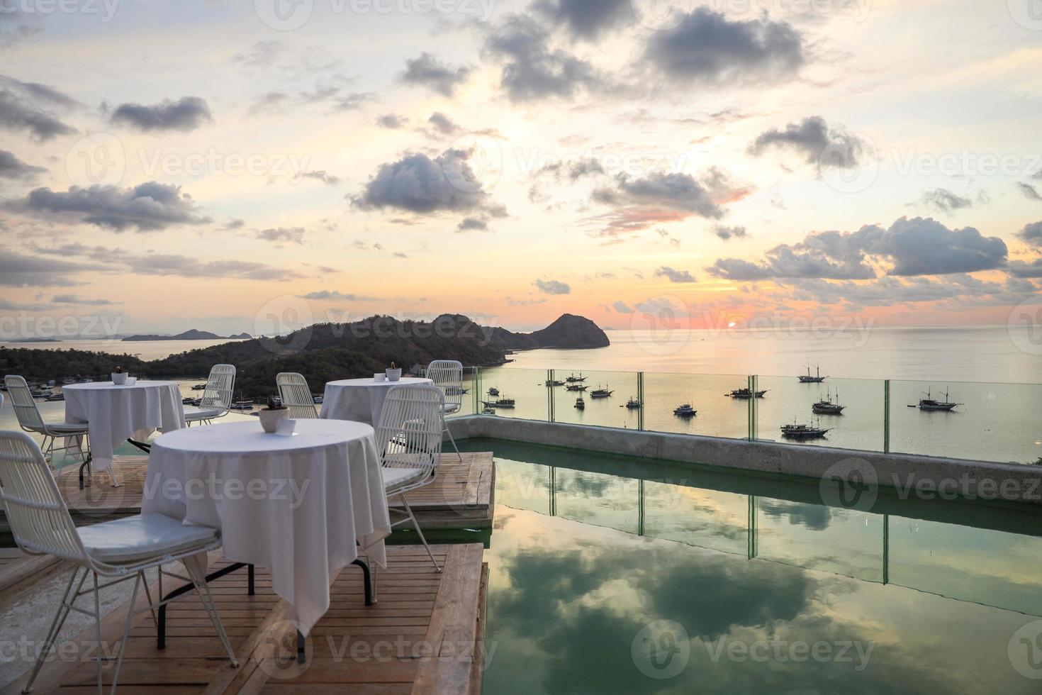 Cozy and romantic cafe with table and chairs on rooftop with sea and sunset view photo