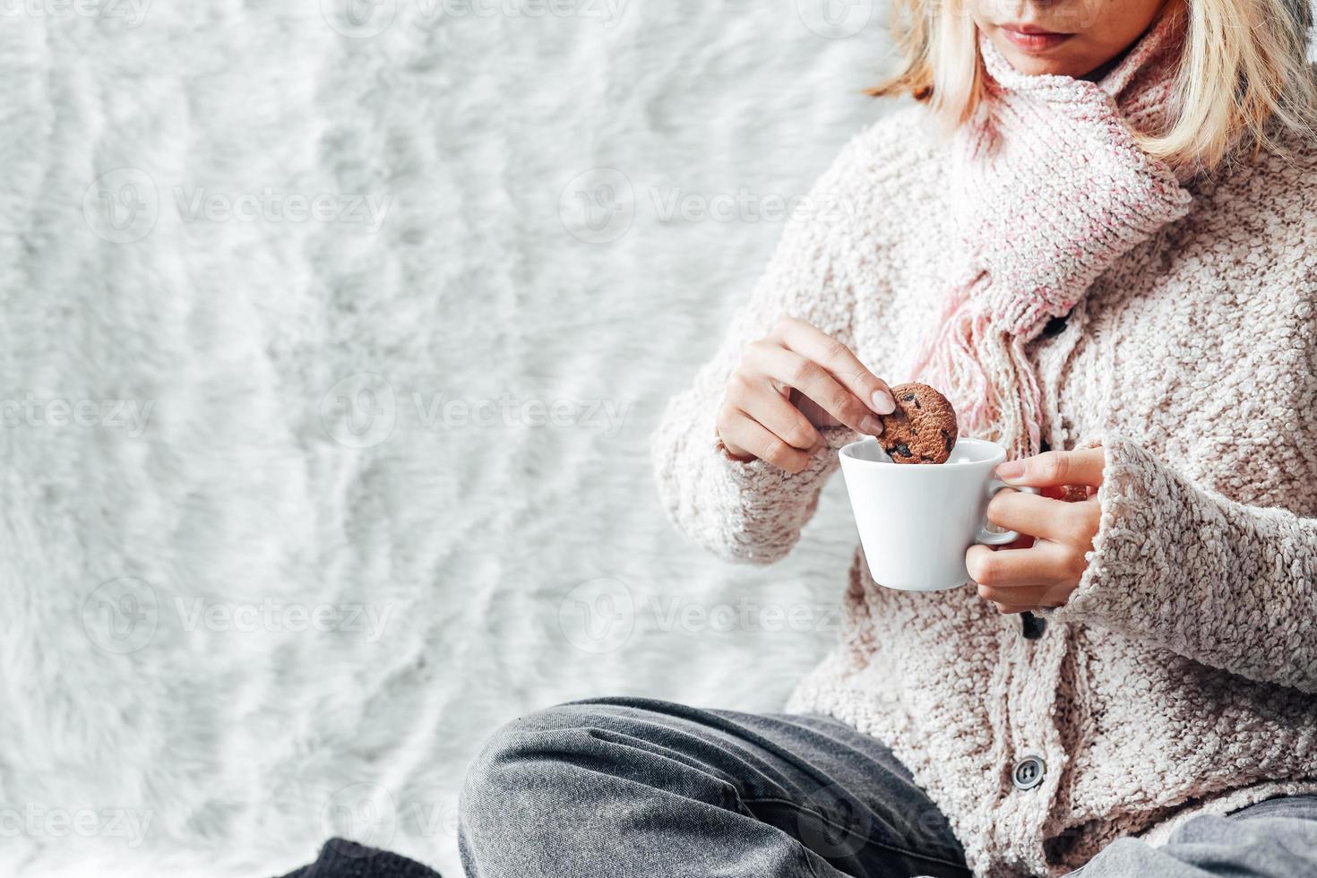 una chica disfrutando de unas galletas y una taza de chocolate caliente en la temporada de invierno foto