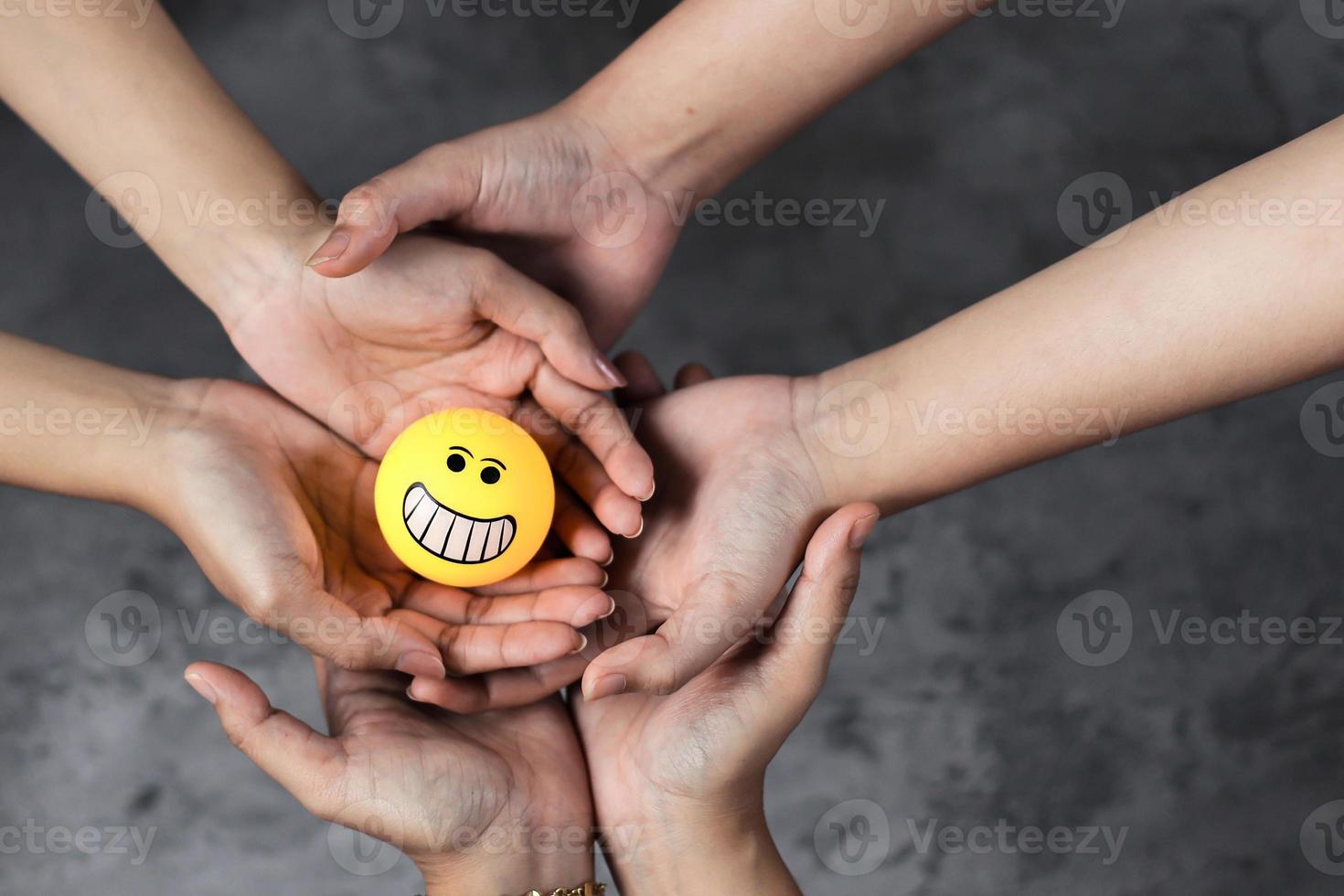 Stack of hands holding smiley emoticons together photo