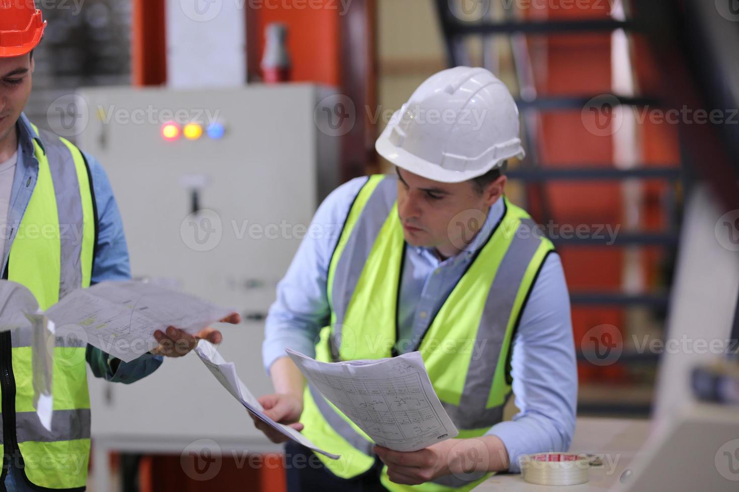 Men industrial engineer wearing a safety helmet while standing in a heavy industrial factory. The Maintenance looking of working at industrial machinery and check security system setup in factory. photo