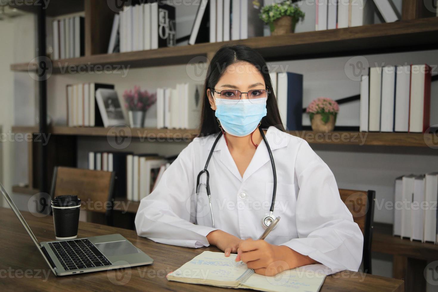 doctora asiática usando una laptop junto a la ventana en su oficina. foto