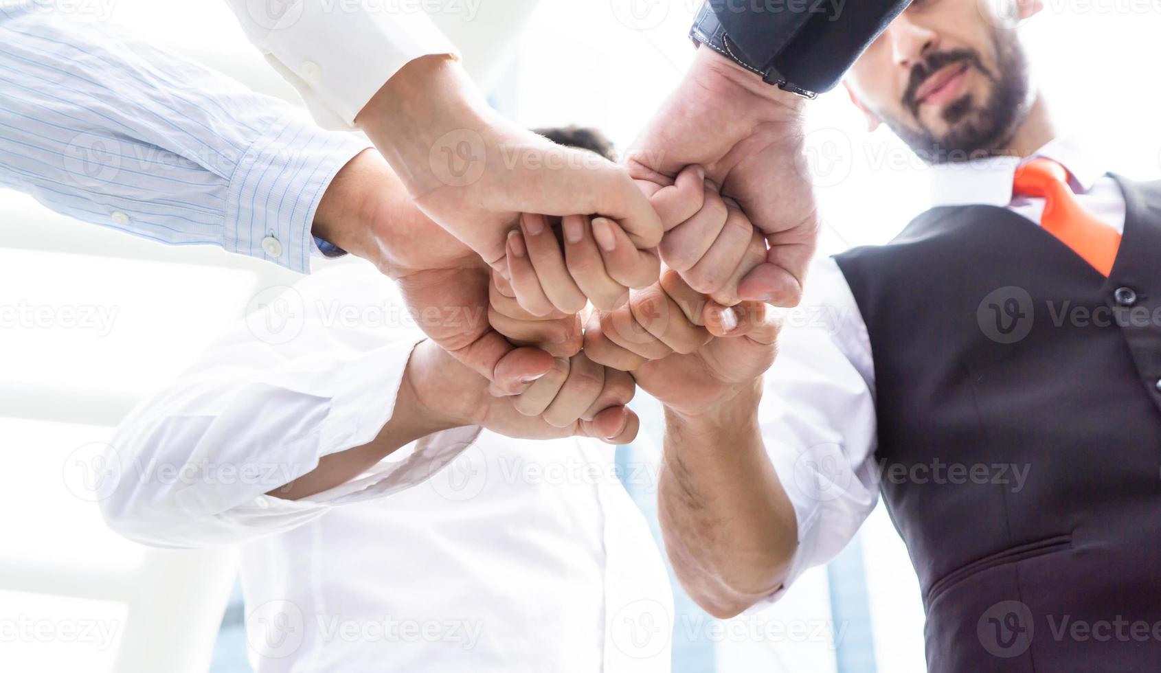 Close up low angle view of young business people putting their hands together. Stack of hands. Unity and teamwork concept. photo