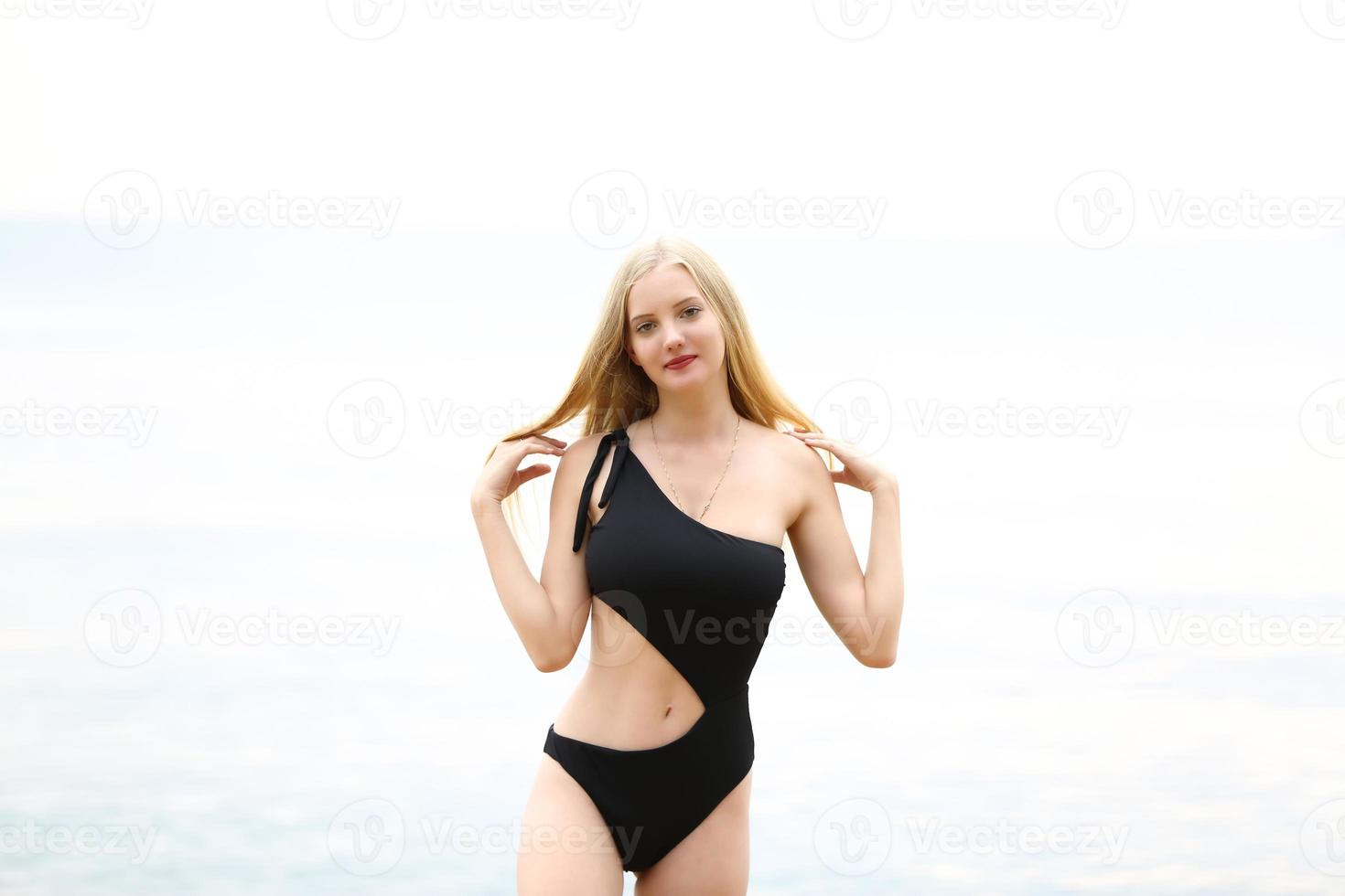 hermosa mujer rubia en bikini negro disfruta del verano en la playa. foto