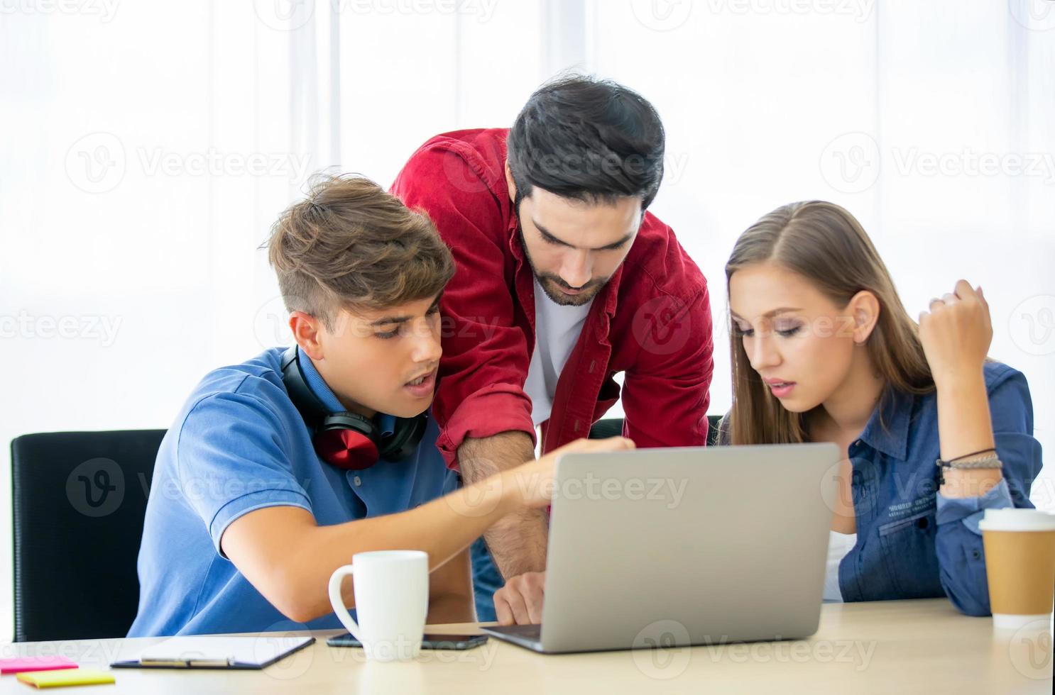 grupo diverso de jóvenes empresarios discutiendo un proyecto de trabajo mientras se sientan juntos en una mesa en una oficina moderna. concepto de coworking foto