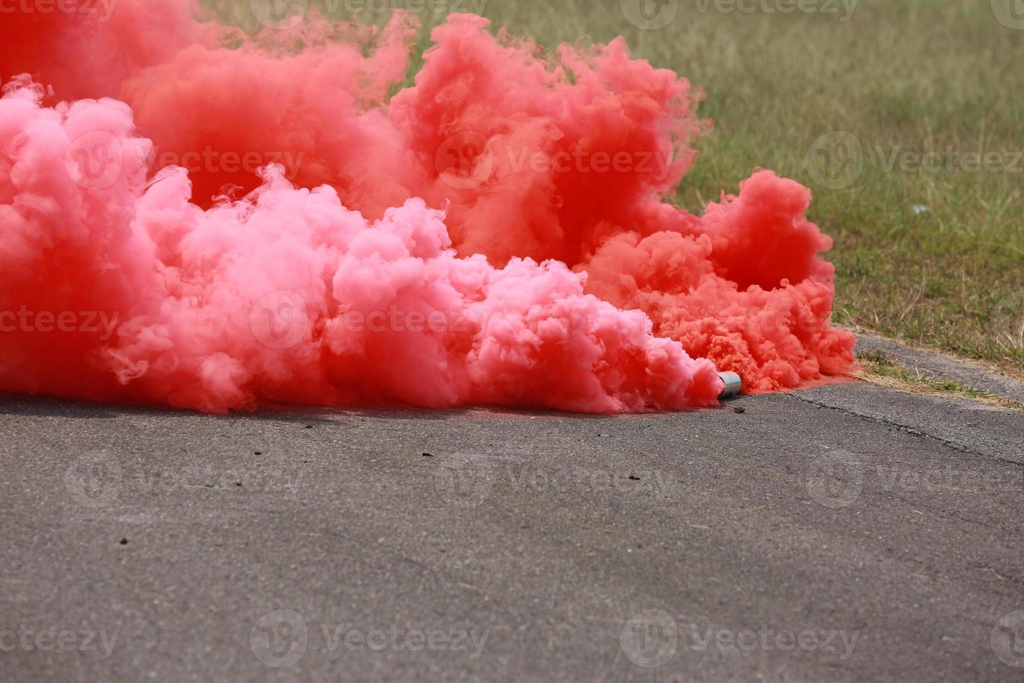 Red smoke for emergency signal on grass for texture for background photo