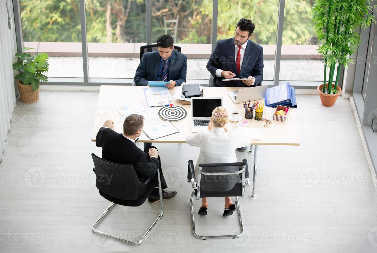 Top view of group of multiethnic busy people working in an office, Aerial view with businessman and businesswoman sitting around a conference table with copy space, Business meeting concept. photo