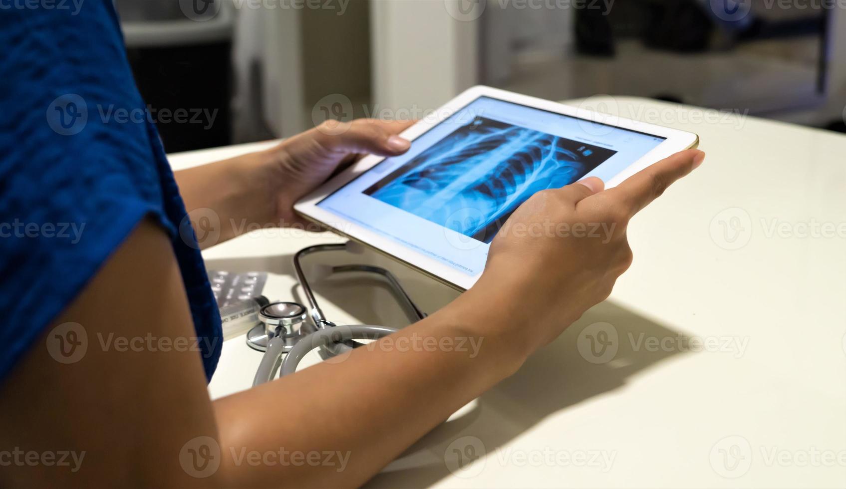 Doctor looking on radiological chest x-ray image on tablet for medical diagnosis photo