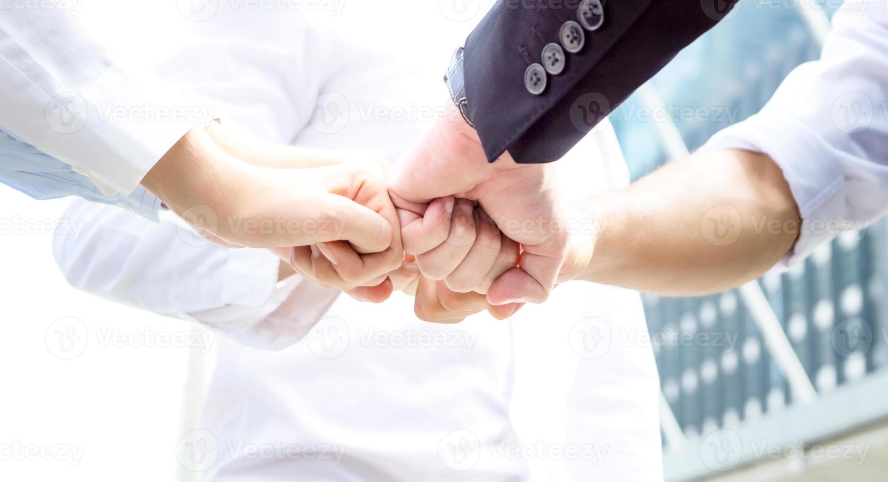 Stack of hands. Unity and teamwork concept. Close up top view of young business people putting their hands together photo
