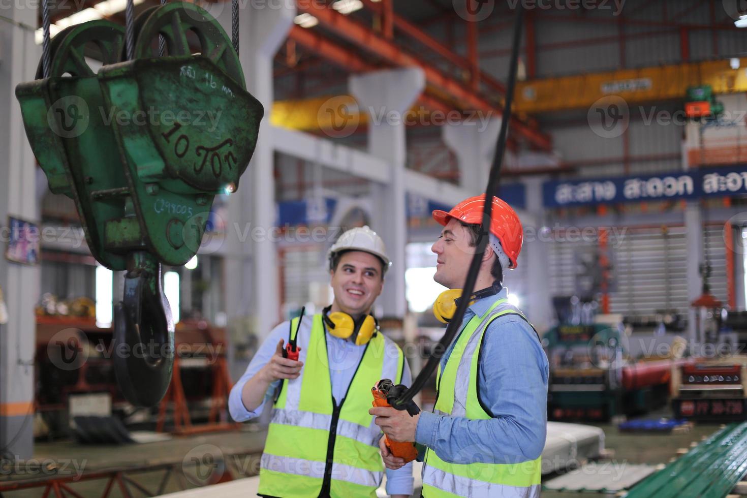 Men industrial engineer wearing a safety helmet while standing in a heavy industrial factory. The Maintenance looking of working at industrial machinery and check security system setup in factory. photo