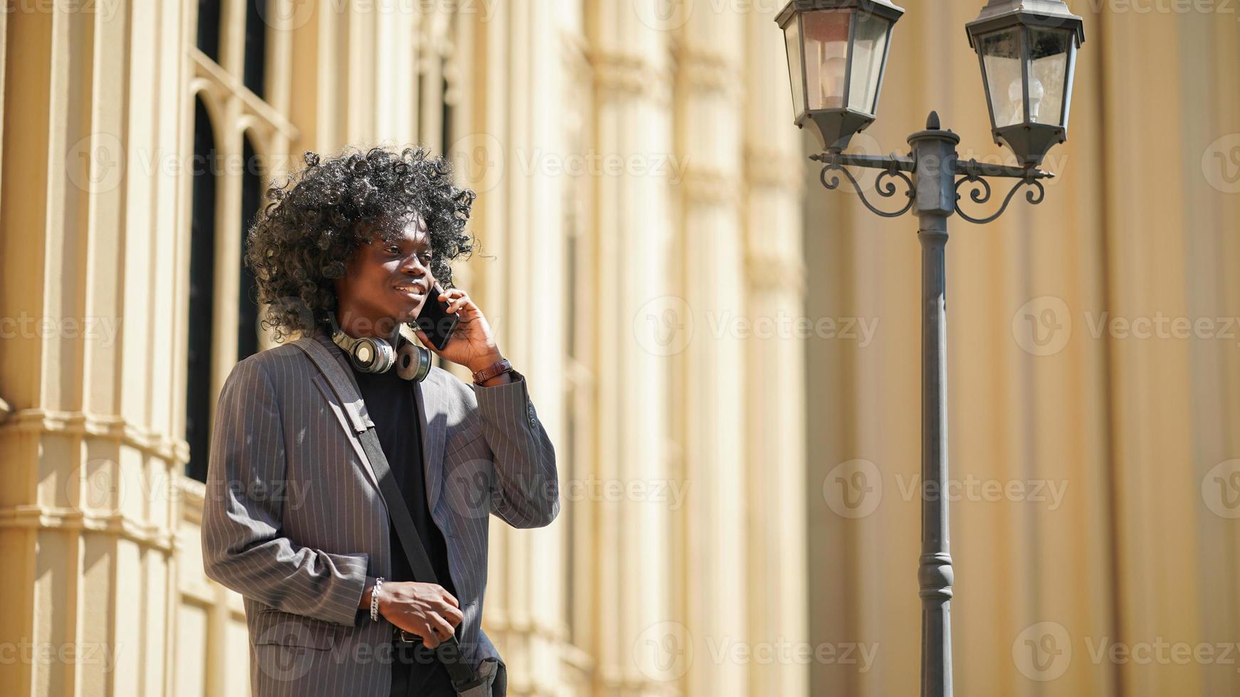 hombre afroamericano divirtiéndose caminando en el centro de la ciudad - joven feliz disfrutando del tiempo una puesta de sol al aire libre - estilo de vida de generación milenaria y concepto de actitud positiva de la gente foto