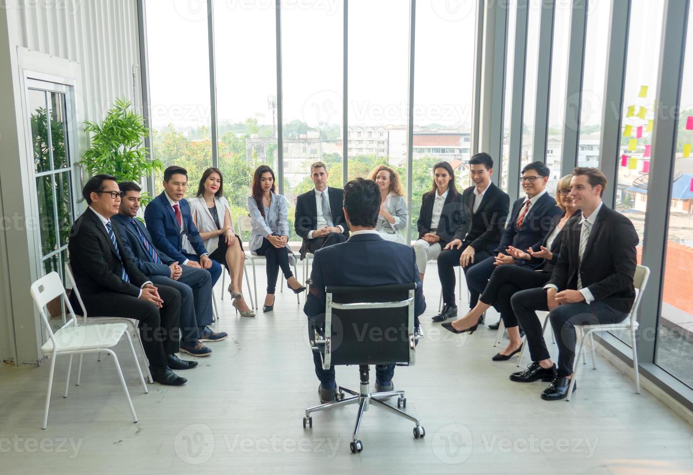 Group of people listening to experienced business professional helping them work out new corporate strategy. photo