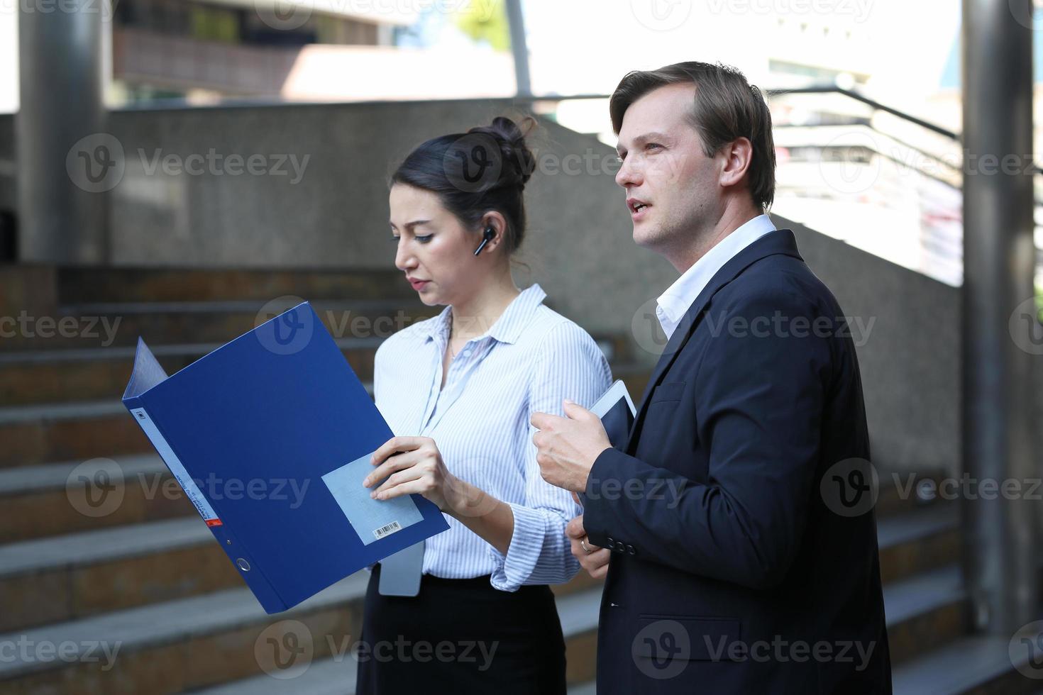 Business people outdoors. Handsome business man and his beautiful female colleague discussing new project while crossing the street, urban background photo