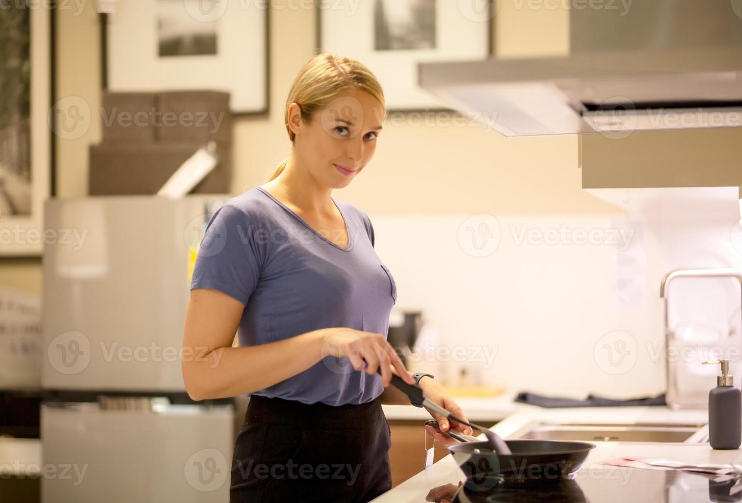 Side view portrait of women in her cooking dinner standing by stove and cooking on a gas hob white tiled wall with warm light photo