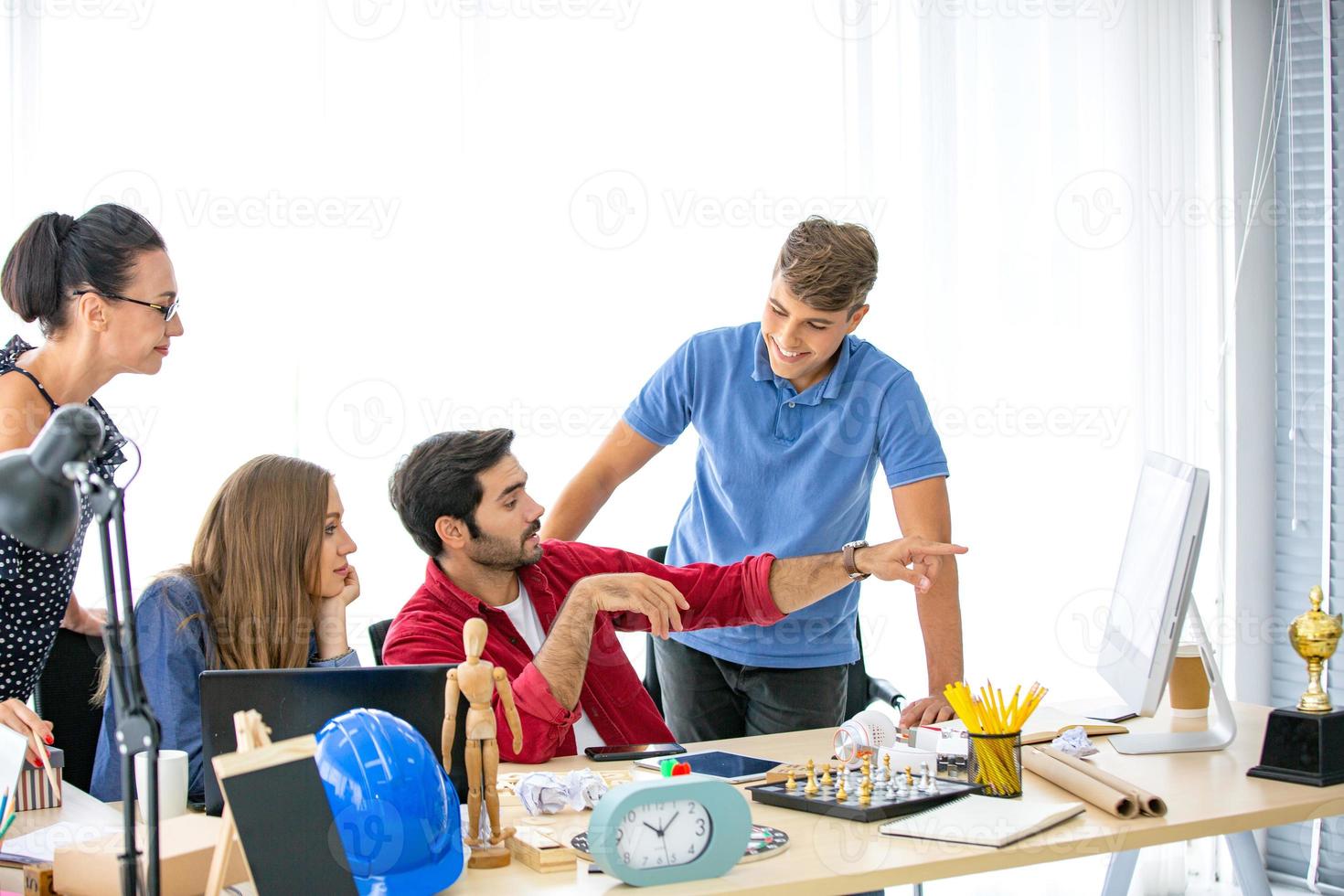 grupo diverso de jóvenes empresarios discutiendo un proyecto de trabajo mientras se sientan juntos en una mesa en una oficina moderna. concepto de coworking foto