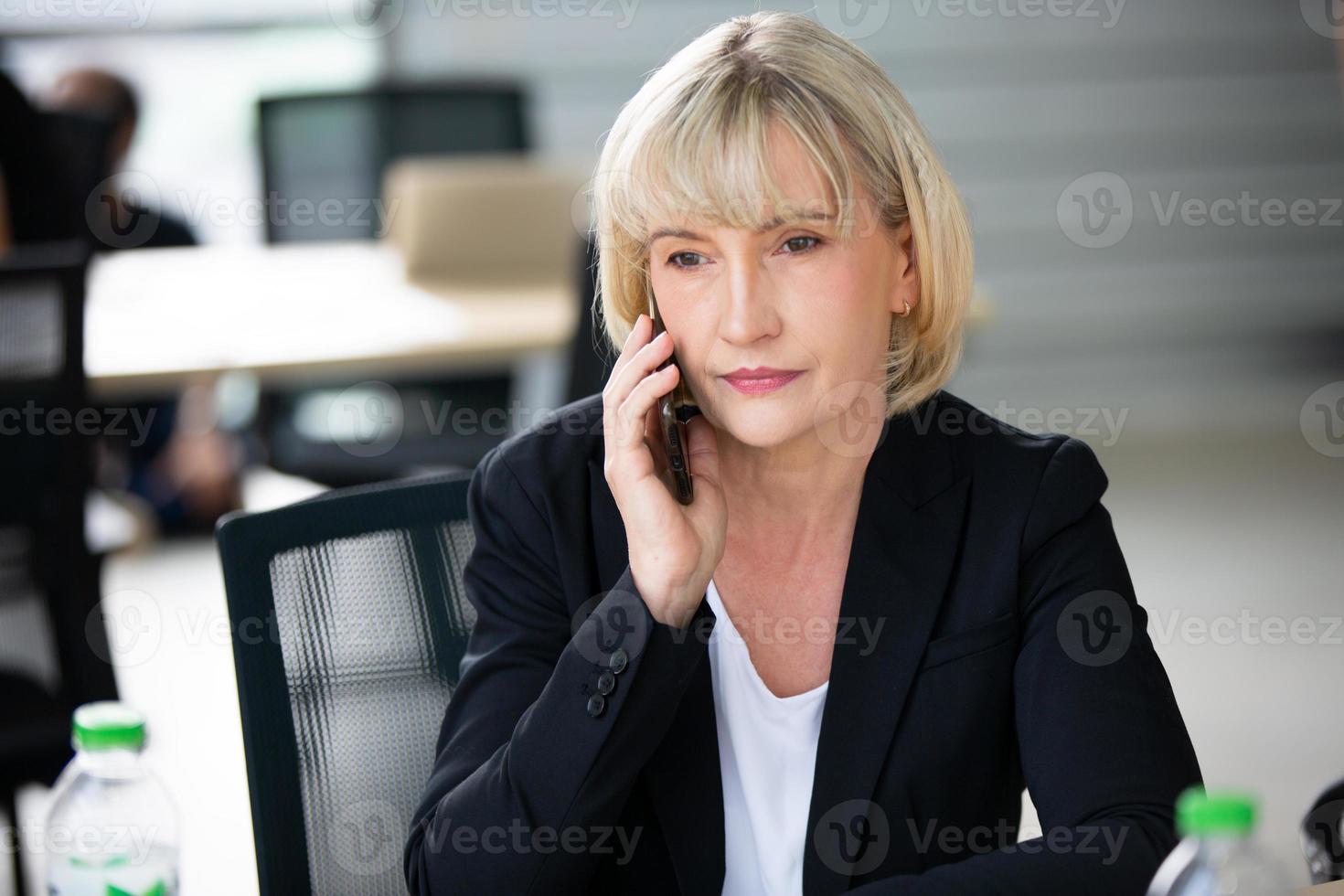 mujer de negocios senior hablando por teléfono móvil en la oficina. foto