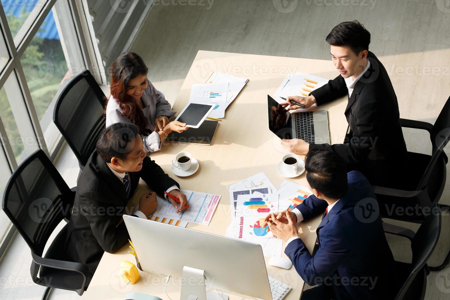 Top view of group of multiethnic busy people working in an office, Aerial view with businessman and businesswoman sitting around a conference table with copy space, Business meeting concept. photo