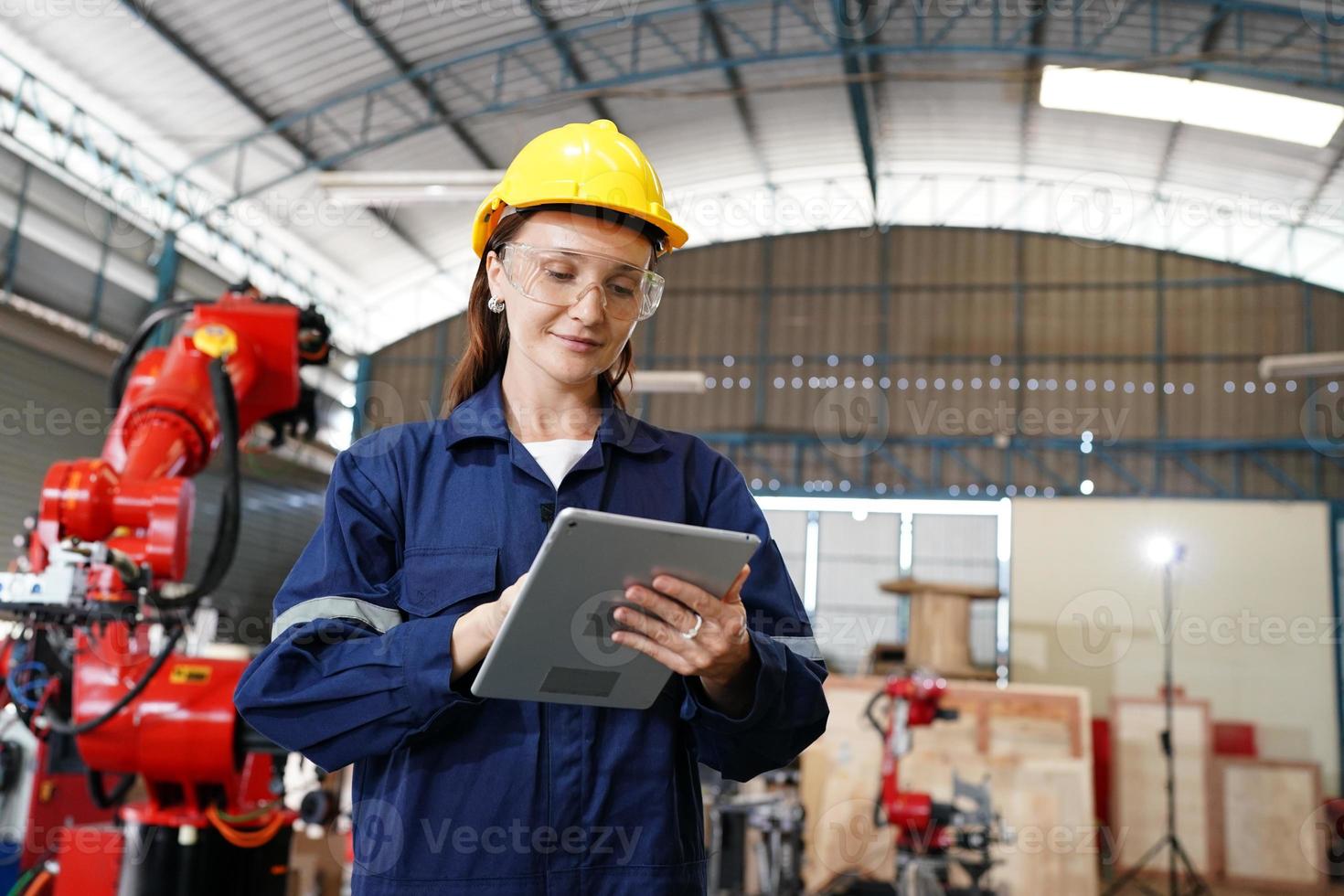 Professional young industrial factory woman employee working with machine part, checking and testing industrial equipment and robot arms in large Electric electronics wire and manufacturing plant photo