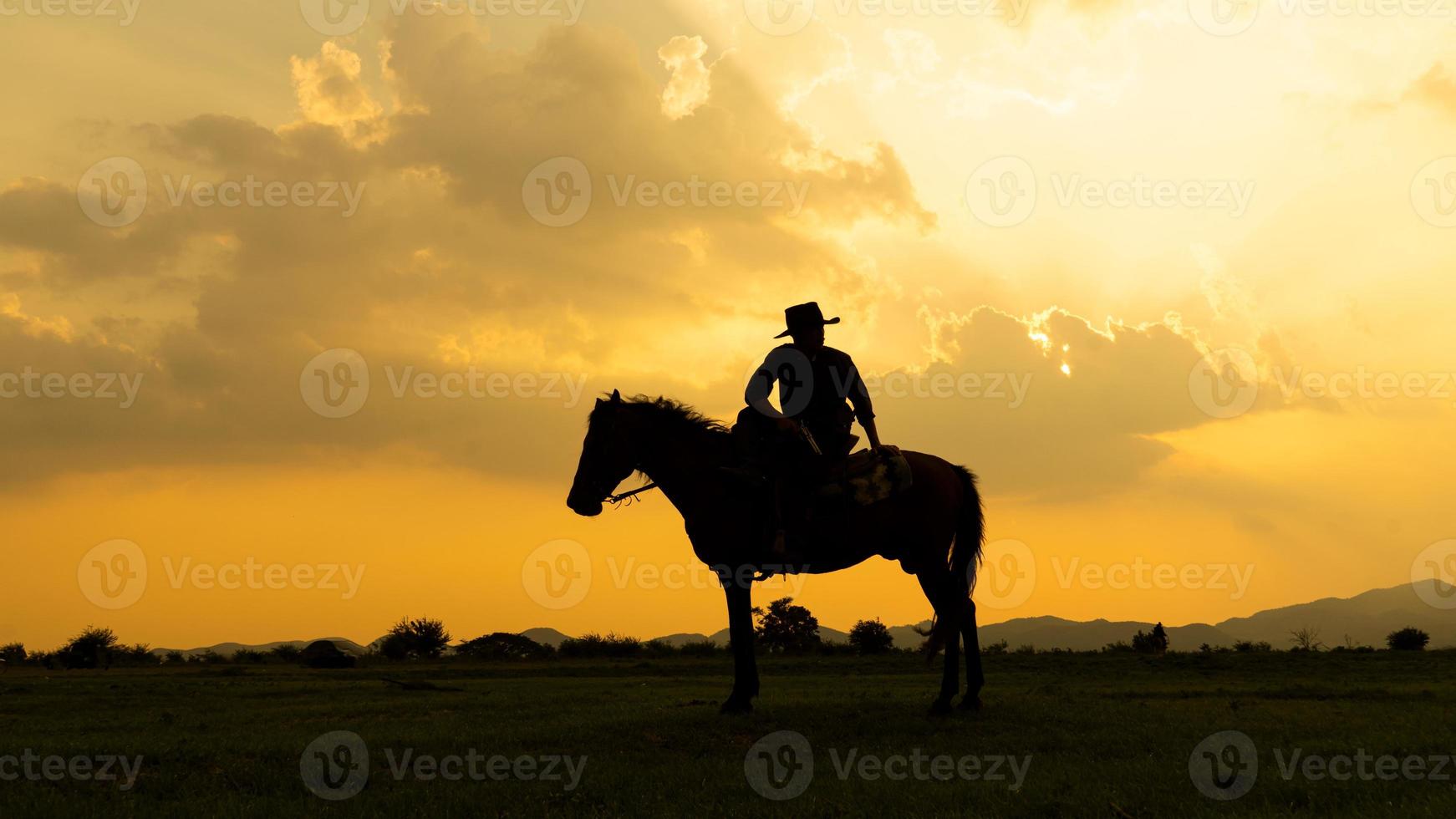 Silhouette Cowboy on horseback against a beautiful sunset, cowboy and horse at first light, mountain, river and lifestyle with natural light background photo