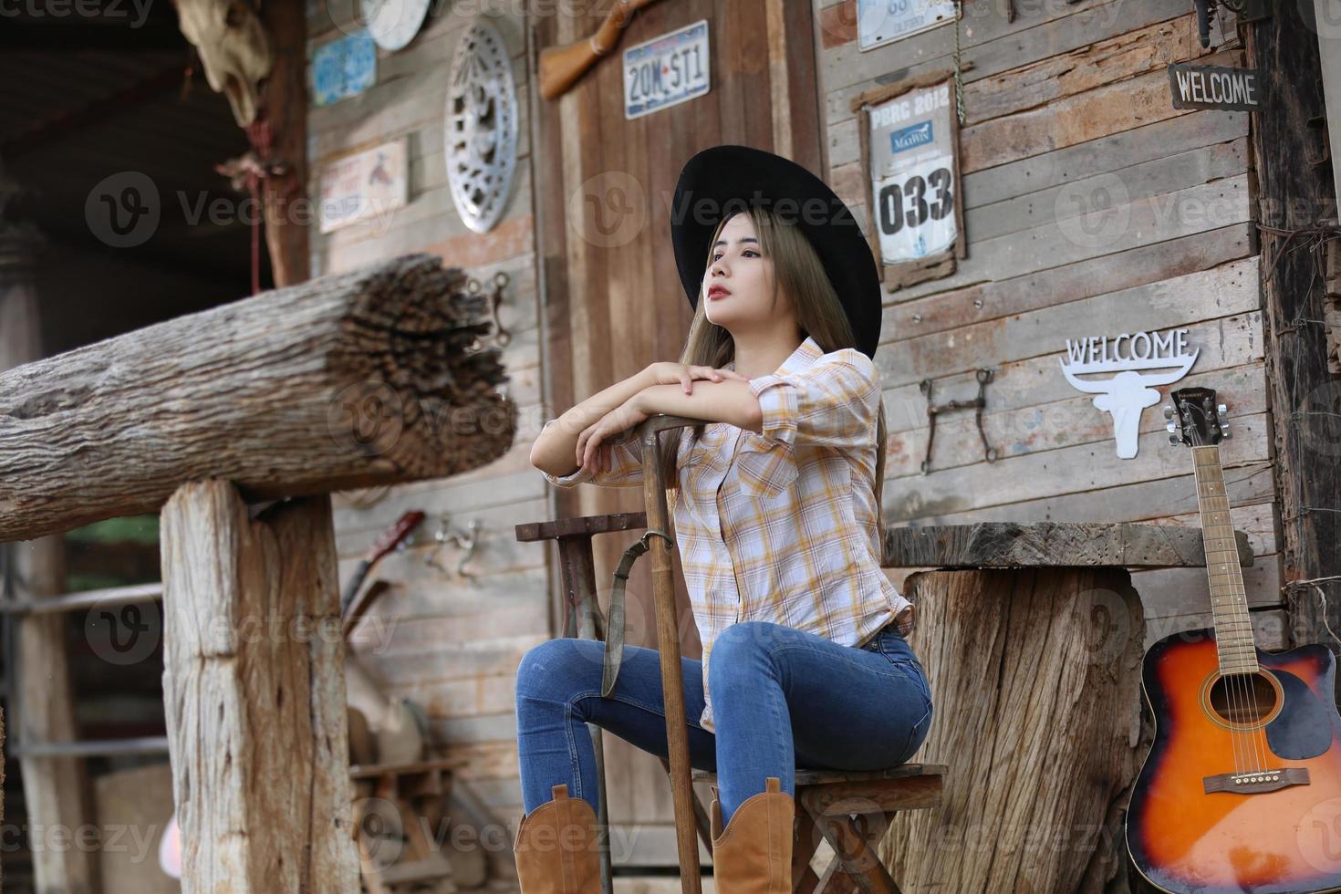 Im a stable girl. A portrait of a beautiful young cowgirl leaning against a wall in a stable at farm. photo