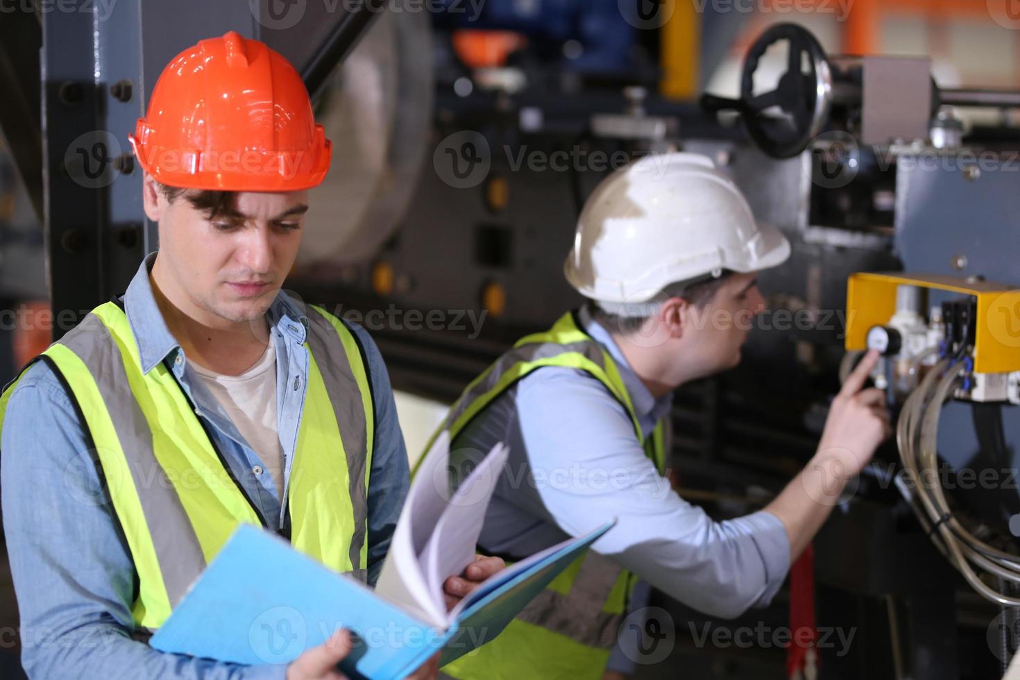 Men industrial engineer wearing a safety helmet while standing in a heavy industrial factory. The Maintenance looking of working at industrial machinery and check security system setup in factory. photo