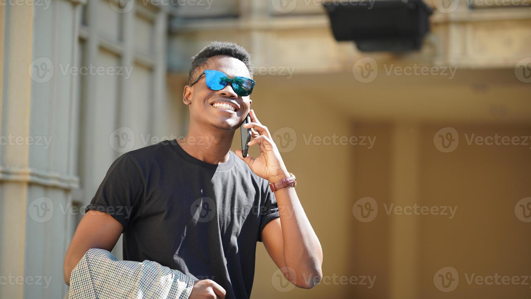 hombre afroamericano divirtiéndose caminando en el centro de la ciudad - joven feliz disfrutando del tiempo una puesta de sol al aire libre - estilo de vida de generación milenaria y concepto de actitud positiva de la gente foto